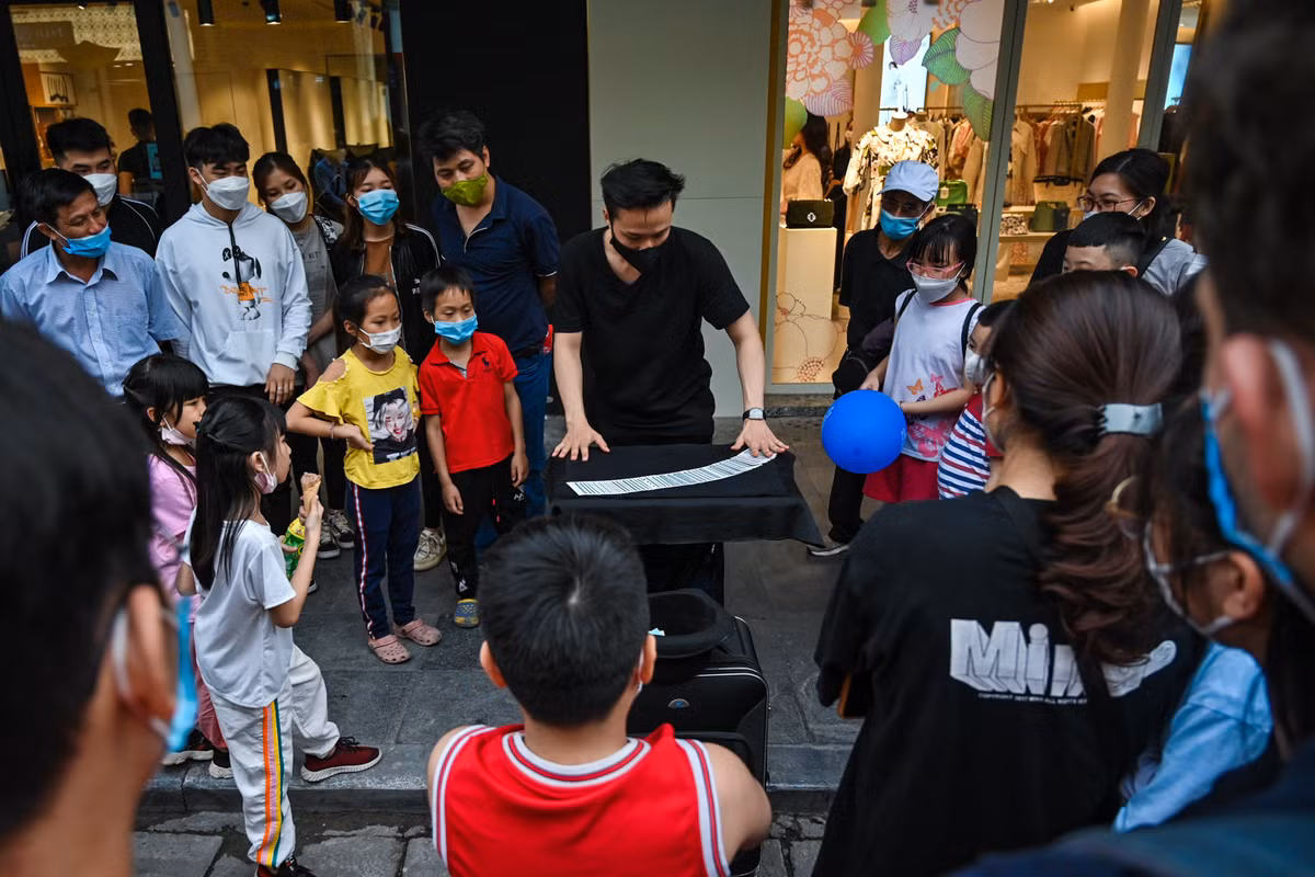 Nhiều hoạt động vui chơi thu hút trẻ nhỏ và cả người lớn. Trong ảnh, một thanh niên biểu diễn ảo thuật trên vỉa hè.