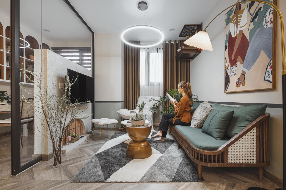 Phòng khách ấm áp, phân chia thành hai khu vực. Một khu tiếp khách và một khu làm việc, đọc sách. Hai bên ngăn cách bằng vách kính, kết hợp lò sưởi giả treo tivi.