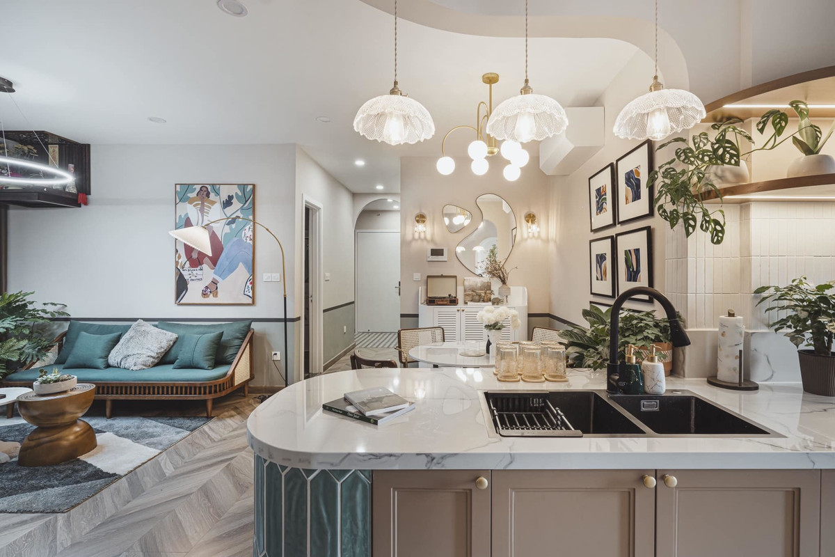 Bếp chạy dài, tạo thành bàn đảo và bồn rửa tay xinh xinh, sang trọng. Bên cạnh là bộ bàn ăn hình tròn tạo cảm giác quây quần, ấm cúng.