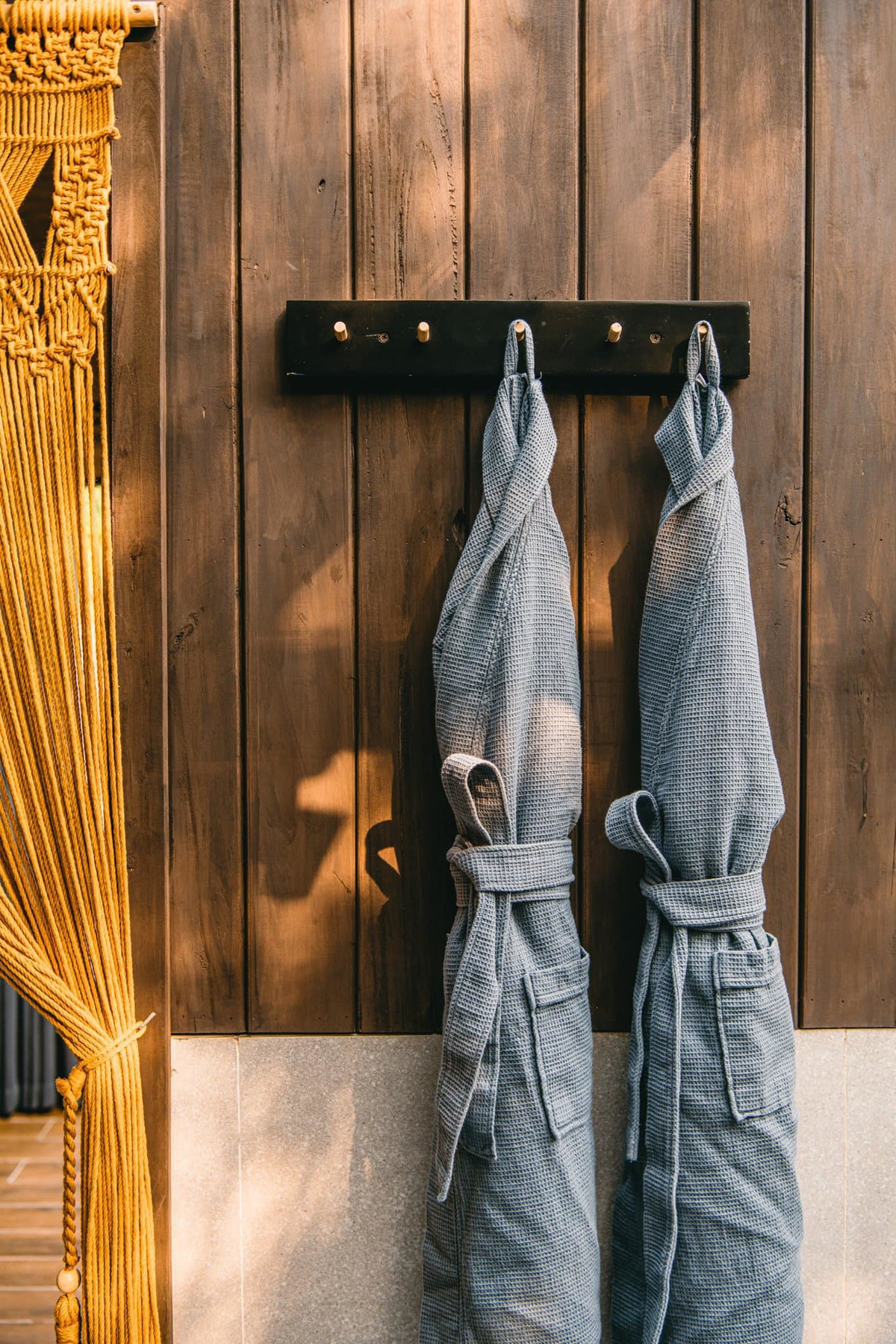 Sàn bồn tắm trải thảm sỏi , tường phòng tắm dùng gỗ màu nâu trầm.