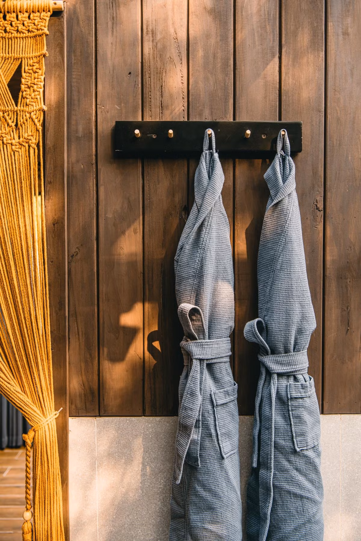 Sàn bồn tắm trải thảm sỏi , tường phòng tắm dùng gỗ màu nâu trầm.