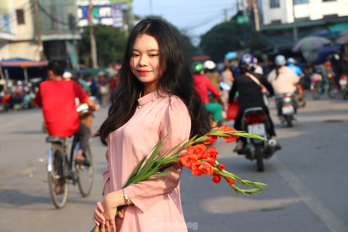 Ôm cành hoa lay ơn, cành đào hay tầm xuân tạo dáng.