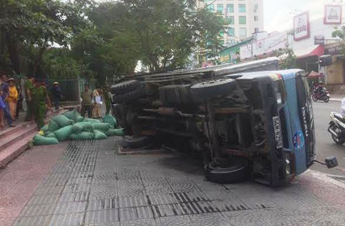 Trong lúc lui xe lên vỉa hè, chiếc xe tải chở nước đá sụp cống lật nhào.