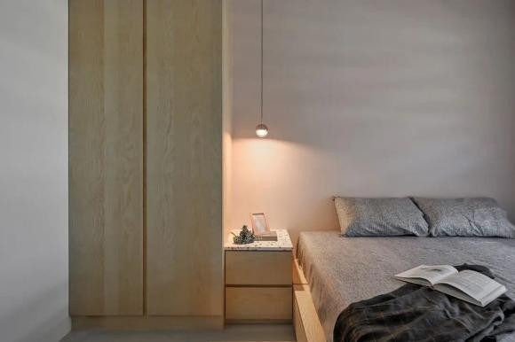 Một chiếc đèn chùm với những đường nét đơn giản được treo xuống, thắp sáng bầu không khí ấm áp. Tủ quần áo thẳng đứng được sắp xếp cạnh nhau. Chức năng ngủ và lưu trữ được đáp ứng trong một không gian nhỏ gọn với loại treo, ngăn kéo và tủ trống.