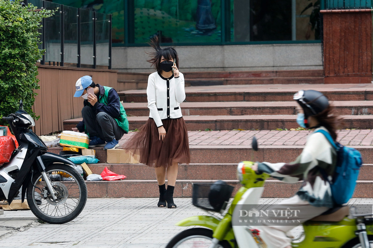 Người đi bộ bị gió thổi bay tóc tại khu vực có nhiều nhà cao tầng. Ảnh Phạm Hưng.