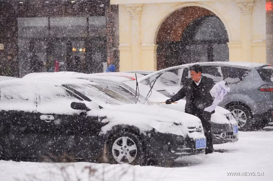 Một người đàn ông ở thành phố Trường Xuân cố gắng gạt lớp tuyết dày bám trên xe hơi.