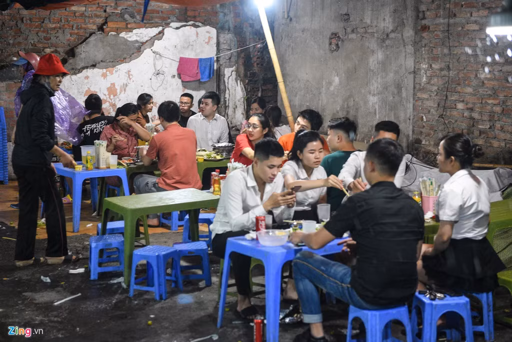 Cửa hàng bán các món lẩu, nướng với không gian chật hẹp, ẩm ướt trên phố Cát Linh gần như kín chỗ vào lúc 21h. Họ ăn uống, nói chuyện tự nhiên, bất chấp việc tiềm ẩn nguy cơ lây nhiễm Covid-19 ở những nơi đông người.