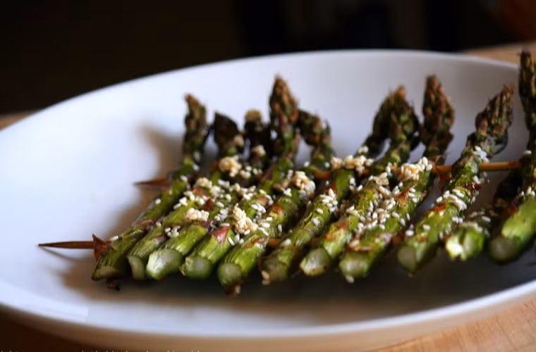 Cho măng tây ra khỏi lò, rắc chút vừng trắng đã rang lên bề mặt để tăng tính thẩm mỹ.