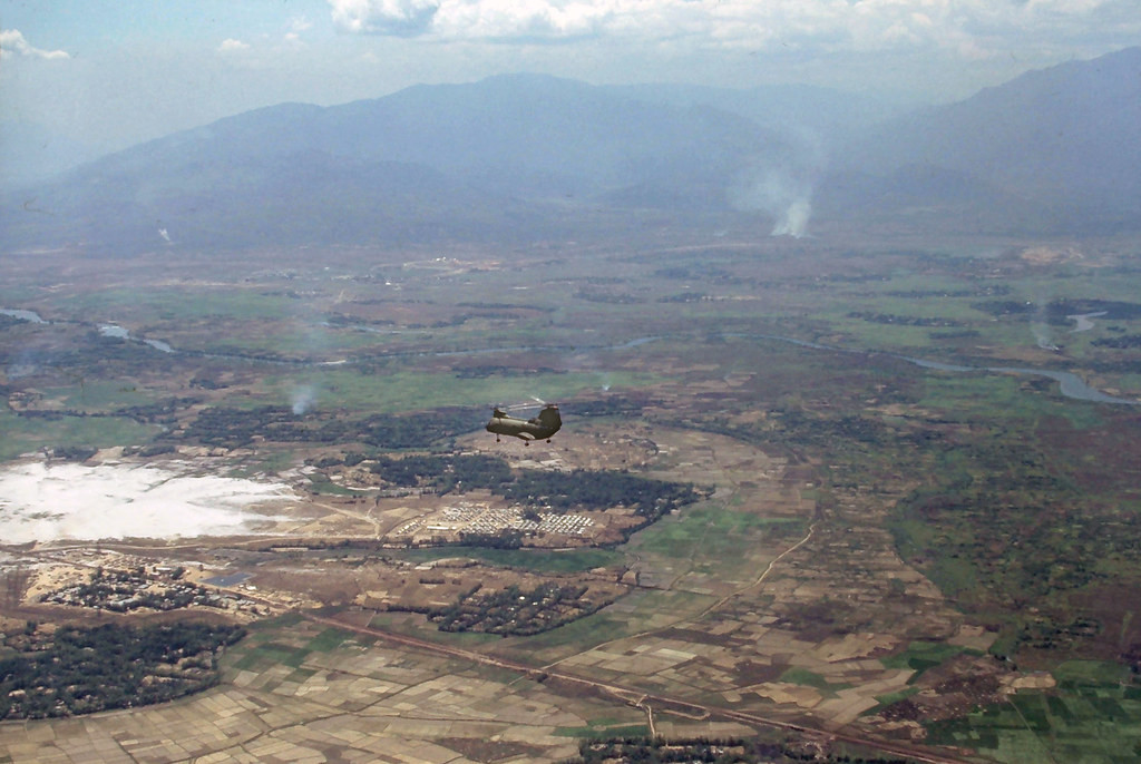Khung cảnh một vùng nông thôn nhìn từ trên cao. Chiếc trực thăng CH-47 Chinook nhỏ như hạt đậu ở giữa ảnh.