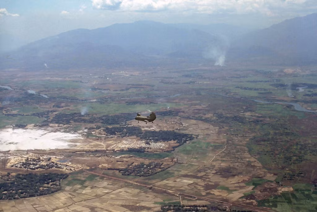 Khung cảnh một vùng nông thôn nhìn từ trên cao. Chiếc trực thăng CH-47 Chinook nhỏ như hạt đậu ở giữa ảnh.