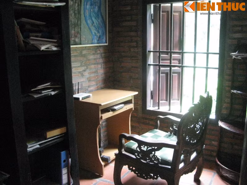 Một bên chái của ngôi nhà đặt một chiếc giường nhỏ cùng tủ gỗ, bên chái còn lại là nơi kê bàn học và tủ sách.