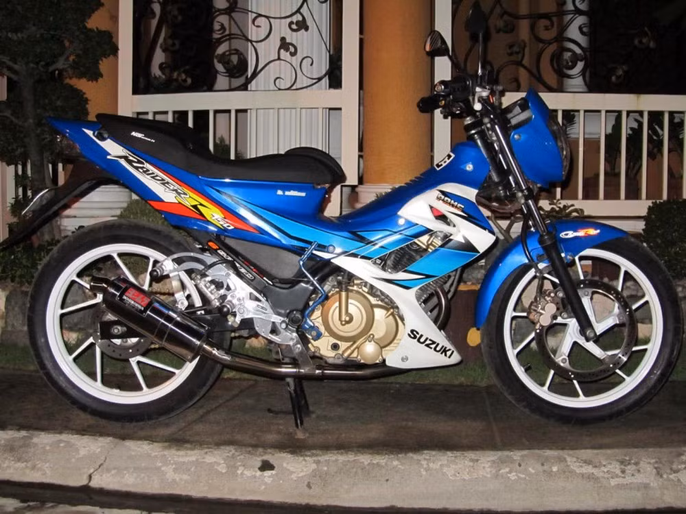 Suzuki Raider 150 vẫn "làm mưa làm gió" trên thị trường Việt và là nguồn cảm hứng bất tận của những tay chơi chuyên độ xe. Điểm nổi bật nhất của chiếc Suzuki Raider 150 này có lẽ là chiếc pô Yoshimura và giò đạp Stinger 120. Pô Yoshimura với lon tam giác thích hợp với hầu hết các loại xe và có giá khoảng 1 triệu đồng.