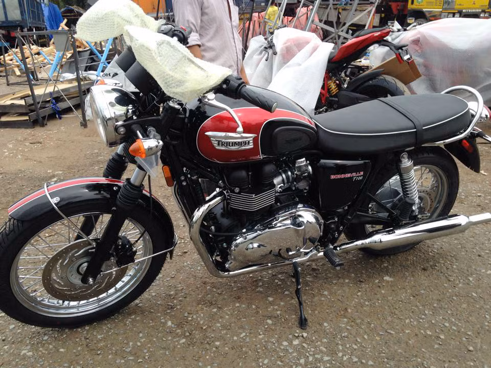 Người anh em Triumph Bonneville T100 màu đen-đỏ. Bình xăng có dung tích 16 lít nổi bật với nắp bình xăng đặt lệch, yên xe dài cùng chiều cao 775mm giúp những người có chiều cao vừa phải cũng có thể chống chân được.