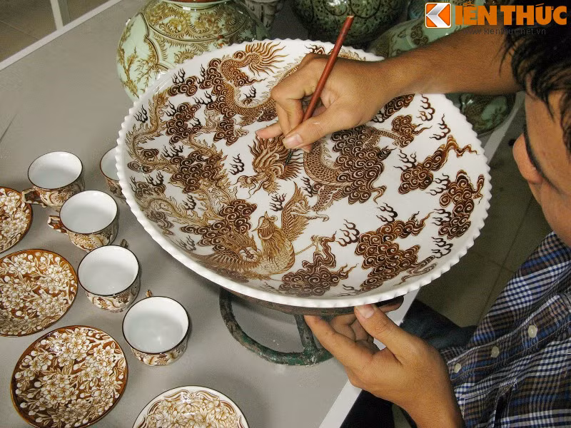 Sau khi nung ở nhiệt độ hơn 800 độ C, sản phẩm được vẽ vàng lên và nung một lần nữa để vàng bám chặt vào sứ và cho độ bền cao nhất. Trong ảnh là nghệ nhân đang thực hiện công đoạn vẽ vàng cho sản phẩm.