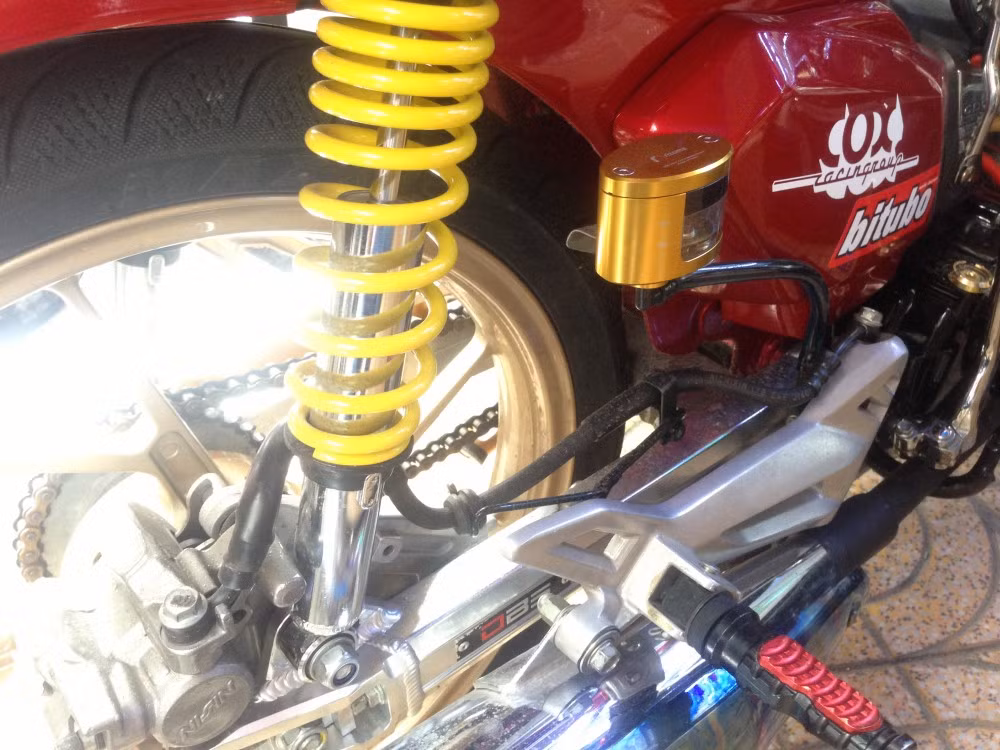 Đồ chơi đằng sau xe gồm: phuộc Nice quen thuộc, gác chân biker, gắp nhôm DBS, bình dầu Rizoma vàng.