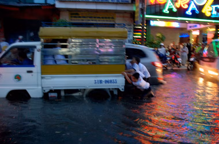 Học sinh phụ đẩy xe qua khu vực ngập. Ảnh: Thanh Niên