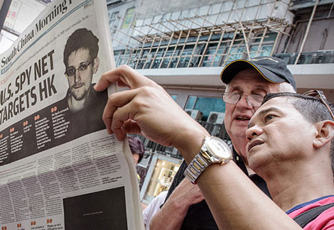 Hai người đàn ông chăm chú đọc tờ South China Morning Post có bài đăng về người thổi còi Snowden hồi tháng 6.
