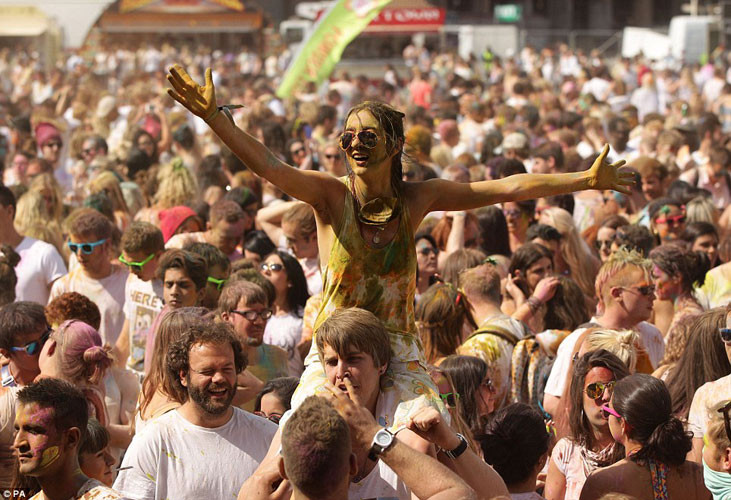 Một cô gái ngồi trên vai bạn trai, hào hứng tham gia lễ hội sắc màu.