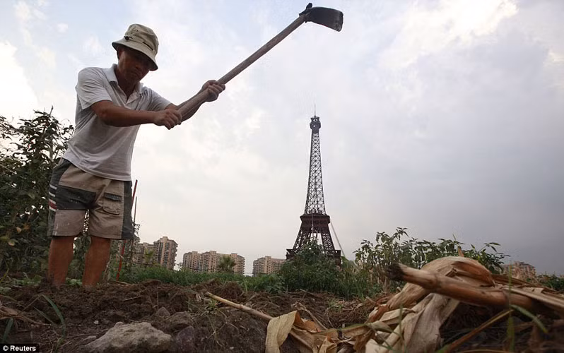 Một nông dân nghèo cần mẫn canh tác trên mảnh đất nông nghiệp mọc đầy cỏ dại ở vành đai bên ngoài Tianducheng.