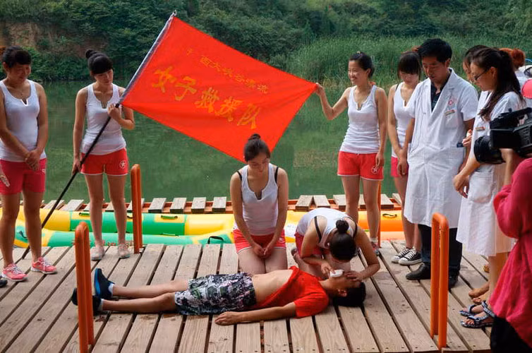 Các cô gái tập trung thành vòng tròn, lần lượt thực hành hô hấp nhân tạo trên người thật.