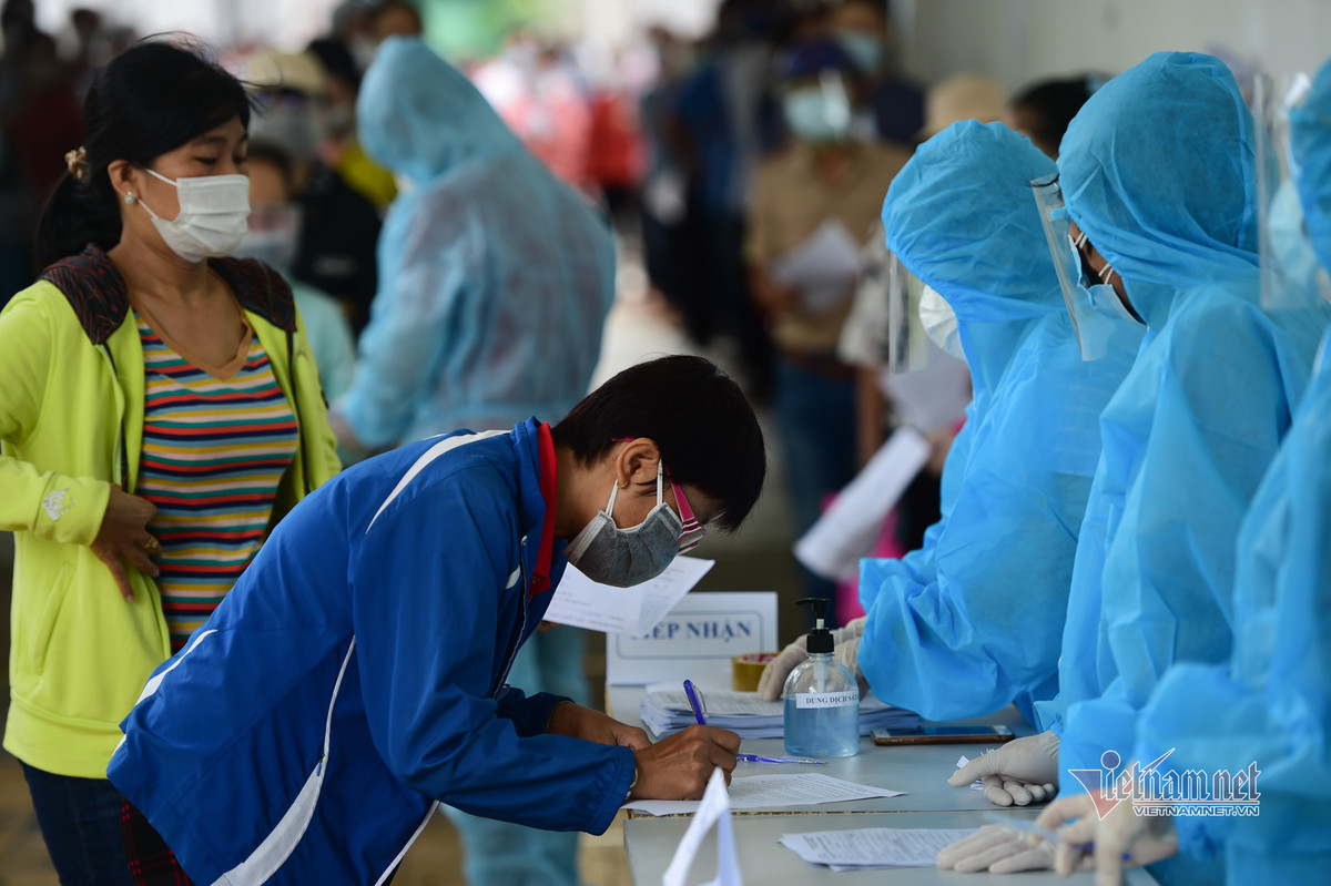 Các công nhân ghi tờ khai trước khi tiêm