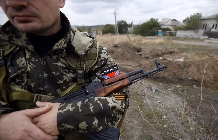 Một dân quân canh gác khu vực hiện trường một hố chôn tập thể.