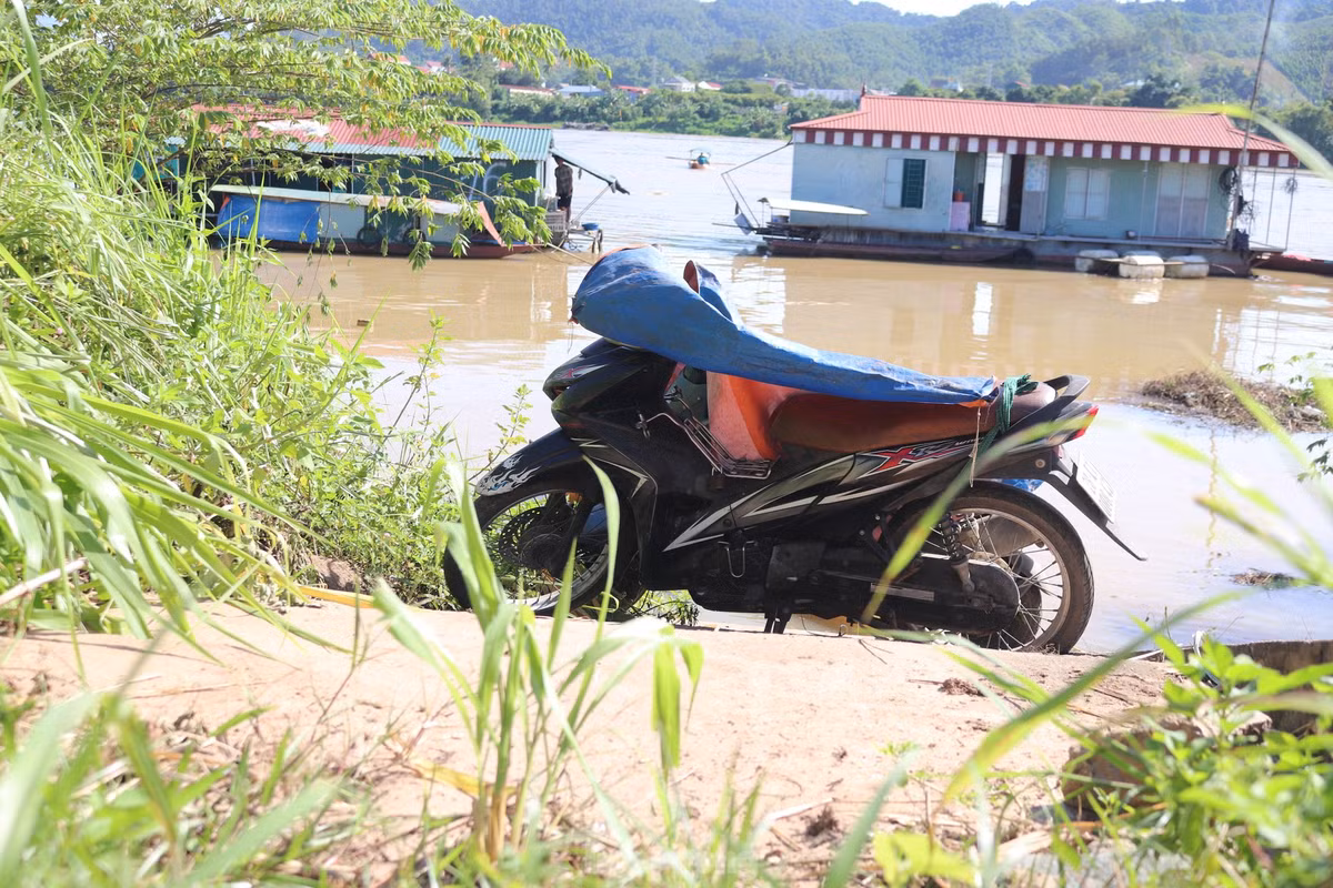 Nơi để xe bị ngập, người dân phải dựng xe trên đường đê và che chắn sơ sài bằng những chiếc bạt.