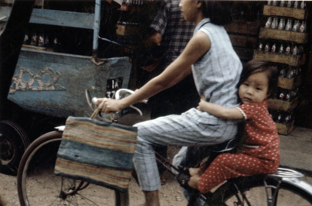 Bé gái được mẹ chở đi bằng xe đạp.