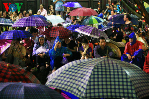 Cơn mưa nặng hạt khiến cho nhiều người phải che ô trong sân chùa.