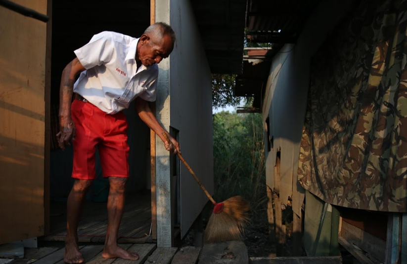 Cụ ông Choochart Supkerd vẫn mặc đồng phục của trường khi quét dọn nhà.