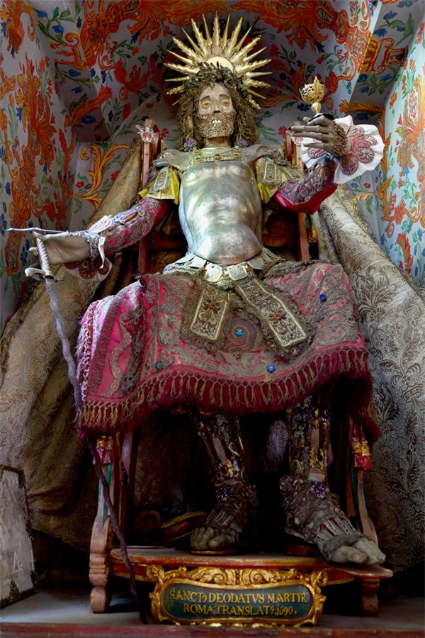 Bộ xương của Thánh Deodatus. Một trong những khám phá thú vị nhất củaPaul Koudounaris chính là bộ xương St. Deodatus được tìm thấy ở Moosburg, Đức, bộ xương nàyvẫn còn nguyên những viên ngọc được gắn trên đó. Ông từngkhông thể giấu được niềm vui sướng: "Nhà thờ cho phép tôi lấy bộ xương ra khỏi hộp, thật sự đó là một cảm giác khó tả, dường như có một sợi dây gắn kết và duyên số đã để tôi được gặp di vậtsau 2 thế kỷ.”Vẫn còn nhiều bí ẩn về những bộ xương nạm ngọc ngà này, nhiều người rất muốn được chiêm ngưỡng chúng.Các bộ xương vô giá này được xem là biểu tưởng sức mạnh mới được tìm thấy của Giáo hội Công giáo ở những khu vực trước đây thuộc đạo Tin lành.