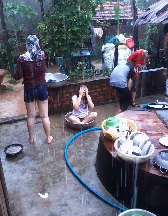 Nam nữ thanh niên tranh thủ gội đầu, tắm giặt, vùng vẫy dưới trời mưa.