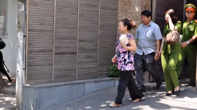 Bà Ngô Thị Minh Phượng (đi đầu) được dẫn từ nhà riêng ra xe của công an - Ảnh: Đông Hà.