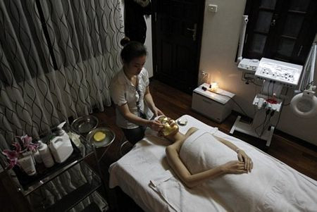 Nhân viên đang đắp mặt nạ bằng vàng cho một khách hàng.