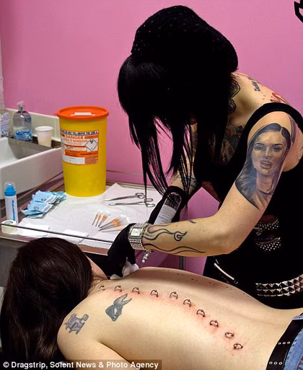 Ban đầu nhà thiết kế sẽ vẽ một chiếc áo lên cơ thể bạn, sau đó từ vị trí vẽ những nút móc của áo, bắt đầu đính từng chiếc khuyên để cố định hình dáng áo trên da bạn.