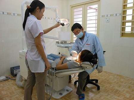 Sau khoảng 3-5 phút khoan lỗ trên răng, bác sĩ chiếu đèn halogen và phun một loại keo nha khoa để gắn chặt viên đá vào răng.