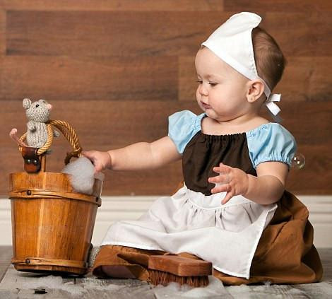 Cô bé Lọ Lem ngồi bên cạnh thùng giặt đồ và nghịch bong bóng xà phòng.