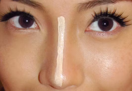 Để khắc phục nhược điểm cho mũi tẹt, bạn cần làm cho hai bên cánh mũi chìm xuống bằng phấn sẫm màu, sau đó dùng phấn màu sáng đánh dọc theo chiều dài sống mũi.