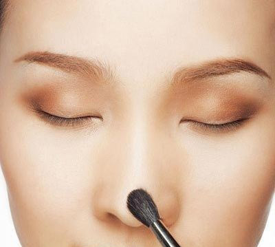 Dùng hai ngón tay xoa phấn đậm hơn dọc hai bên cánh mũi. Đồng thời dùng bút che khiếm khuyết để che bớt những vùng da tối màu hoặc tấy đỏ ở vùng mũi.