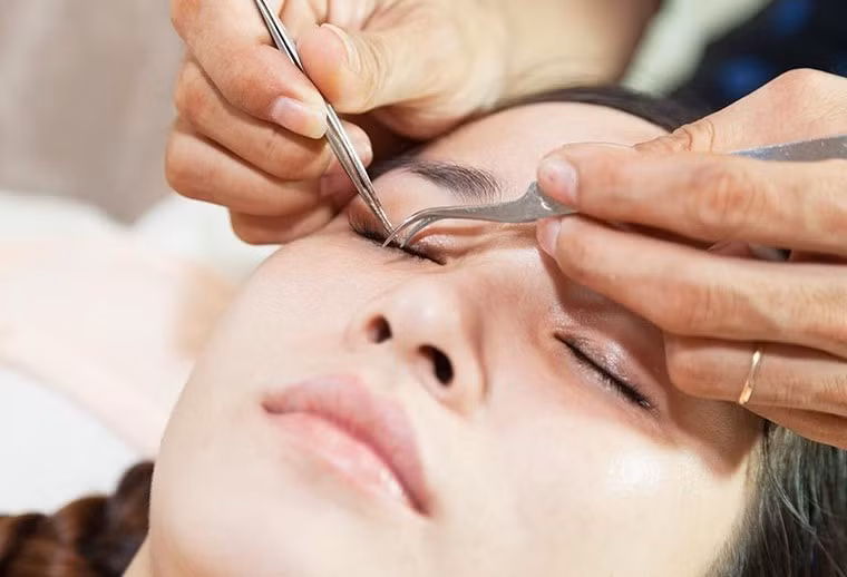 Người thợ rẽ lông mi thật để đưa mi giả đính vào sát mí.