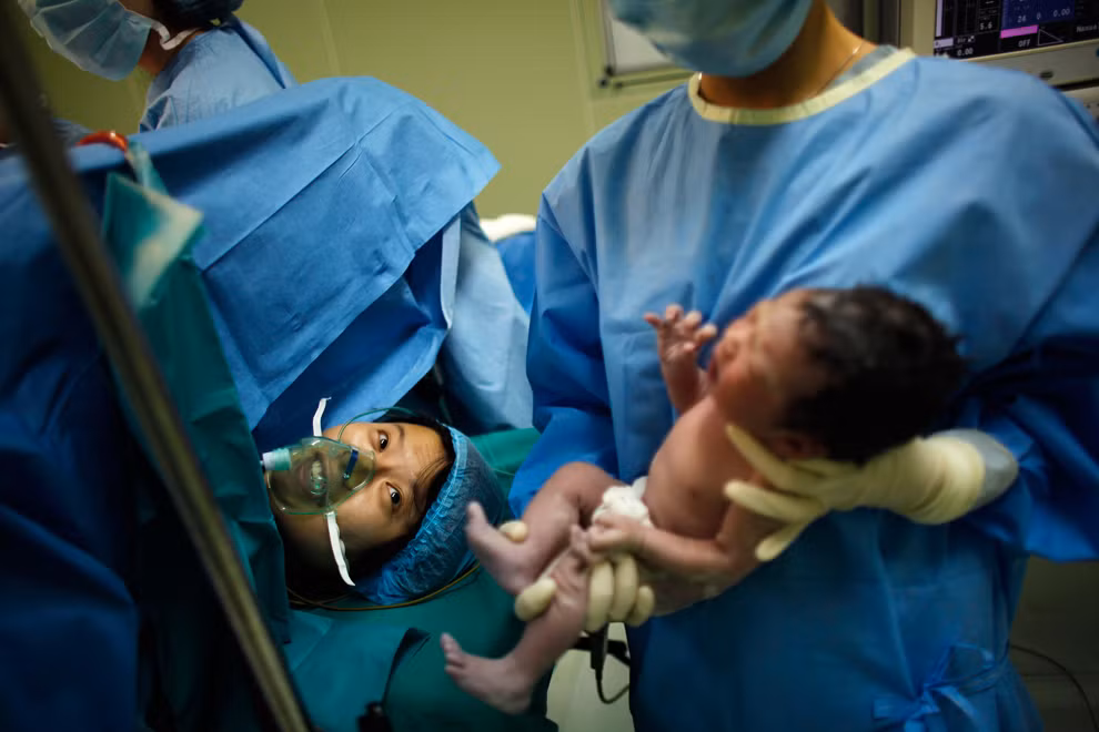 Yang Huiqing ngước mắt ngắm nhìn đứa con của cô lần đầu tiên sau khi mổ sinh ở bệnh viện Ruijin, Thượng Hải.