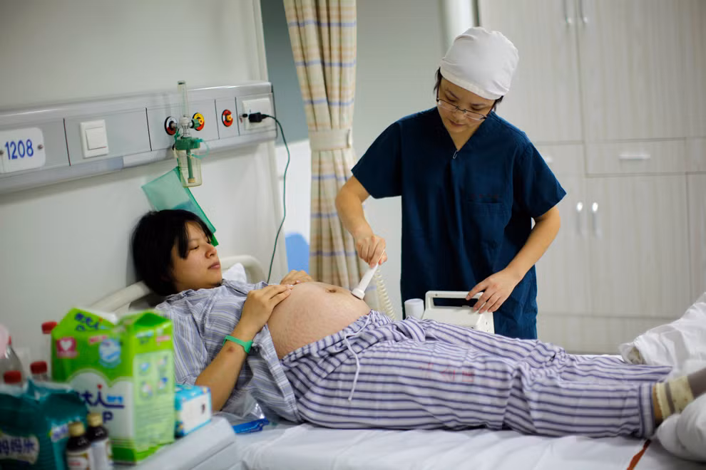 Y tá đang kiểm tra tình trạng bào thai cho cô Yang Huiqing trước khi cô được sinh mổ tại bệnh viện Ruijin, Thượng Hải. Yang và chồng cô là Chen Yiming, cả hai đều sinh ra trong quy định có một con duy nhất.