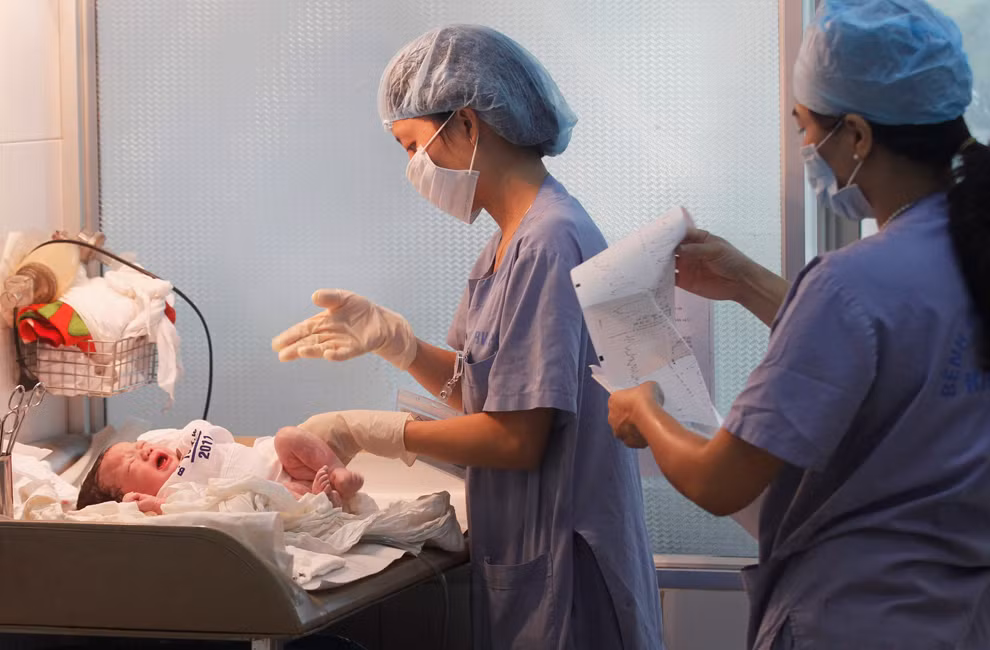 Một y tá đang chăm sóc cho em bé mới sinh.
