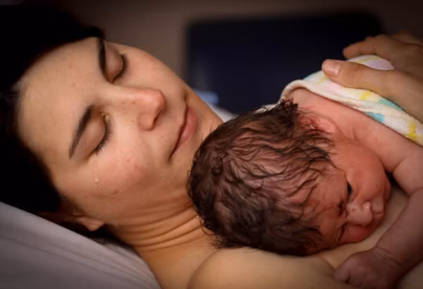 Người mẹ không kìm nén được giọt nước mắt hạnh phúc khi ôm đứa con vừa chào đời trong vòng tay.