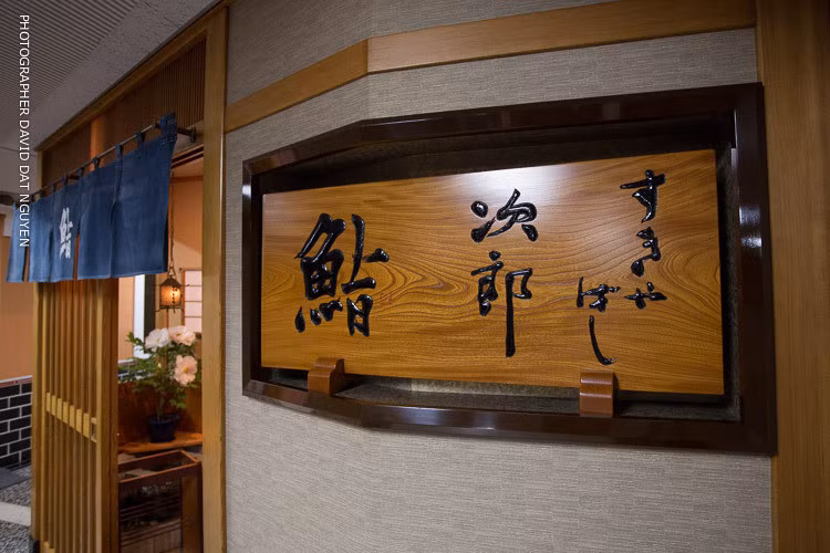 Tấm biển quảng cáo của nhà hàng được làm bằng gỗ đặt một bên tường.