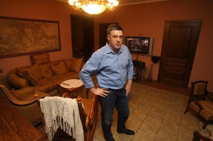 Phòng khách đơn giản với đèn chùm, ghế salon, tivi, tranh thêu ...