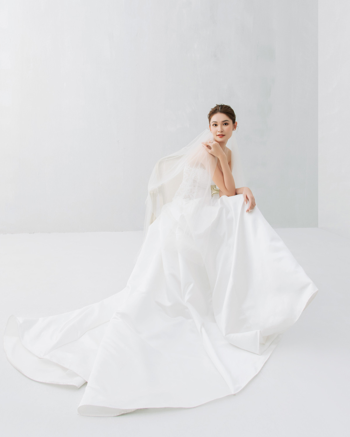 Cô dâu tiếp tục chọn mẫu đầm trễ vai nhẹ nhàng, thanh thoát. Điểm nhấn là phần đuôi bồng bềnh và veil dài hơn 2 m.