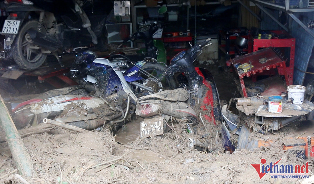 Đường từ thị trấn Mường Xén vào bản Hoà Sơn (xã Tà Cạ), nước lũ vẫn đang chảy xiết, lượng bùn đất kéo về rất lớn, chất cao như núi. Nơi thấp từ 50 – 70cm, nơi cao lên đến gần 2m. Hàng trăm ngôi nhà bị chôn vùi trong bùn đất, tài sản của nhiều hộ dân bị lũ cuốn trôi. (Nhiều xe máy bị nhấn chìm ở gia đình ông Hải - Ảnh: Trần Tuyên)