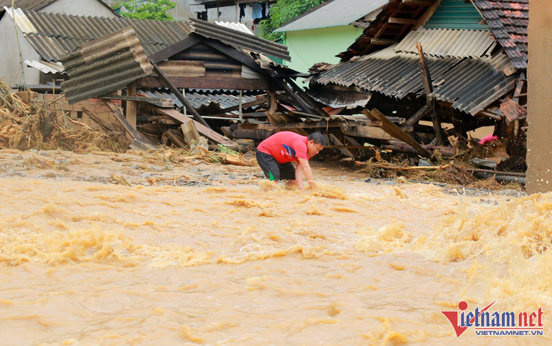 Một người dân đang nỗ lực tìm kiếm các vật dụng chìm trong nước lũ. 
