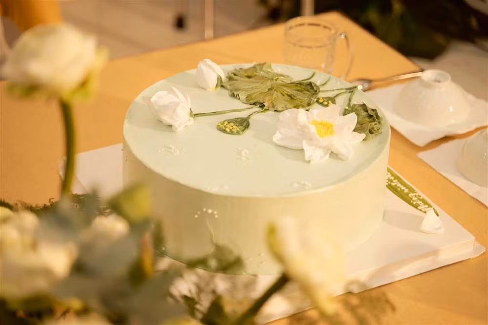 Chiếc bánh sinh nhật được trang trí với gam màu xanh trang nhã, bên trên là hoa sen.